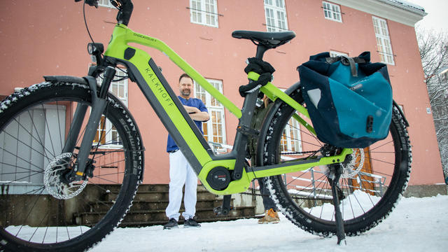 Grønn sykkel og mann med blå skjorte i bakgrunn