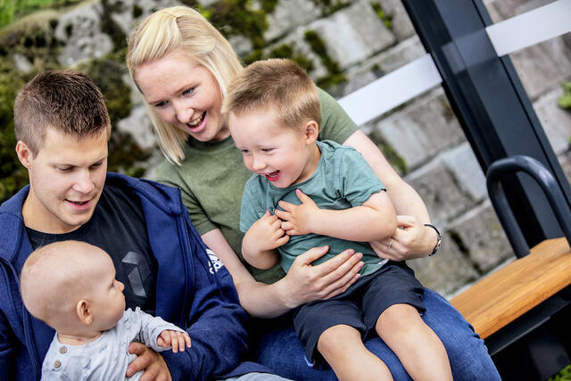 Familie på tre sitter og venter på bussen. 