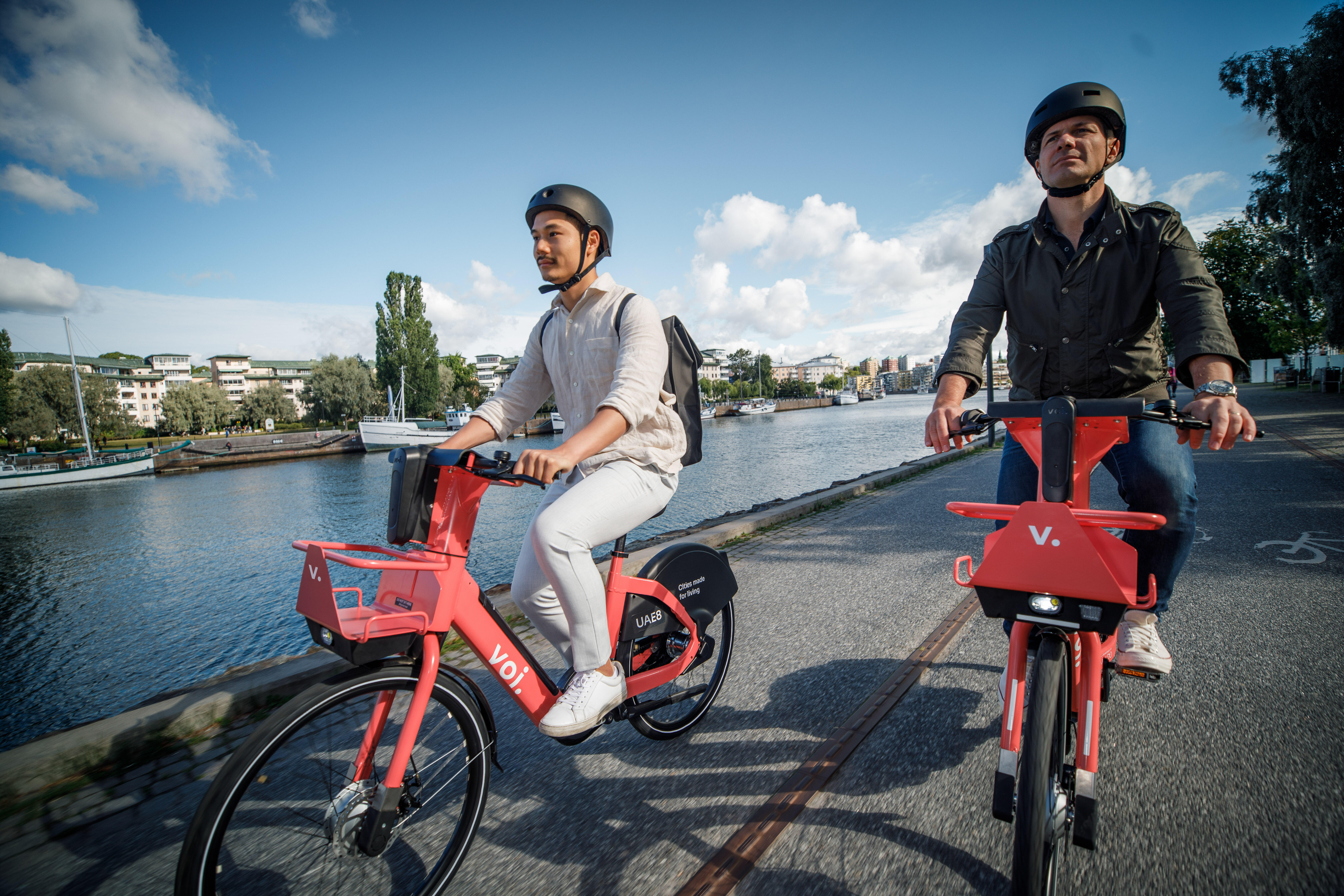 To personer på Voi-sykler i by i Europa.