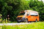 Oransje AtB Bestill minibuss på landevei ved skog