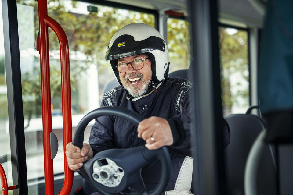 mann med ratt i hendene sitter fremst og later som han kjører bussen