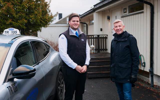 Taxisjåfør og passasjer utafor bilen