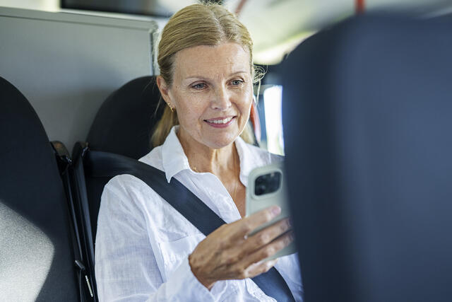 Dame sjekker telefon på bussen