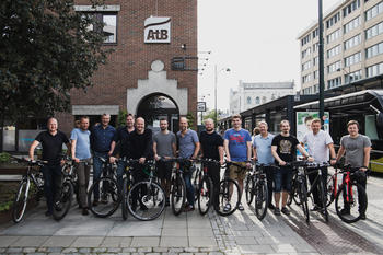 13 menn smilende med sykler